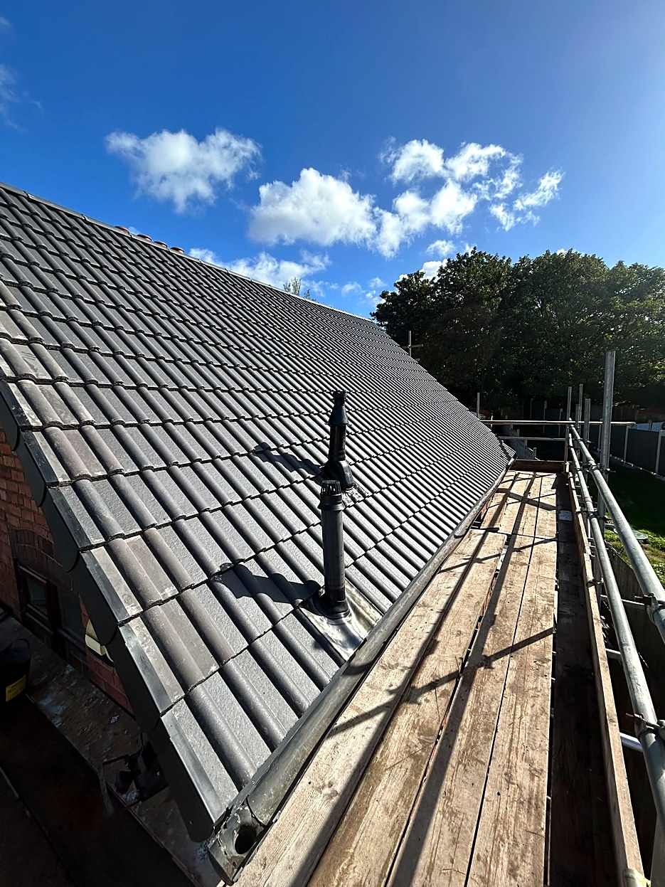 New grey interlocking roof tiles with dry verge and a flue vent
