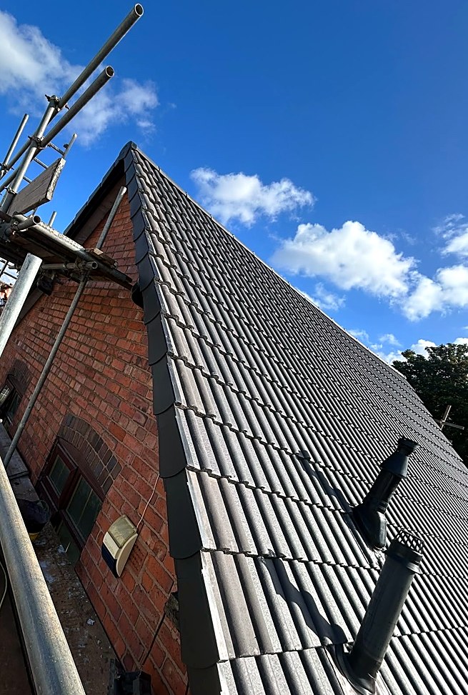Brick gable end with a newly tiled roof and dry verge